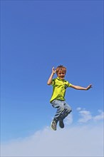 Symbolic image: Boy jumping into the air, blue sky in the background