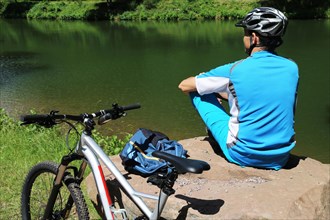 Symbolic image: Mountain biker taking a break at a lake (Edenkobener Tal, Palatinate Forest)