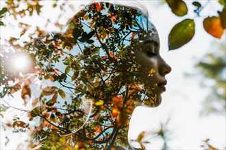 Portrait in double exposure, face and leaves in the light of the sunset, symbolic image for