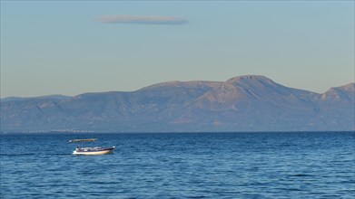Lonely boat on the wide blue sea with mountains in the background and clear sky, Gythio, Mani,