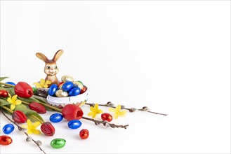 Colourful Easter decoration with an Easter bunny and a variety of chocolate eggs, white background,