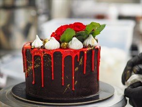 A delicious cake adorned with roses and chocolate ganache, focusing on the dripping icing