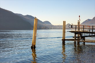 Jetty on Lake Lugano with Mountain and City in a Sunny Day with Clear Sky in Porto Ceresio,