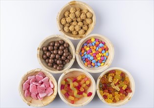 Various sweets arranged in wooden bowls on a white background