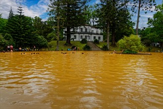 Bathers in the large yellow thermal lake and white spa centre, thermal baths, Furnas, Sao Miguel,