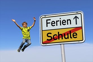 Symbolic image: German town exit sign with the words Schule/Ferien. In the background, a boy is