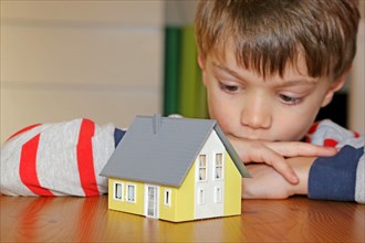 Boy looks longingly at a model house