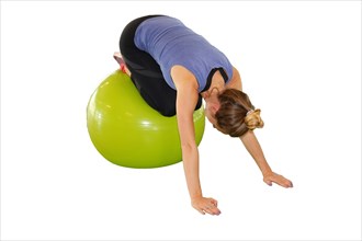 Symbolic image: Young woman doing exercises on an exercise ball against a white background