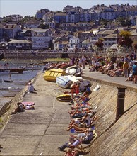 People sunbathing on the quay at the harbor in St Ives, Cornwall, UK, Europe. Scanned 6x6 slide