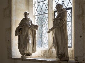 Two statues of monks or saints standing by a window inside village parish church at Dauntsey,