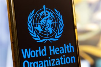 Symbolic image: Smartphone with WHO (World Health Organisation) logo against a blurred background