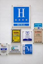 Various hotel and tourism related signs on white wall background, Hotel La Vinuela, Axarquia,