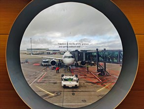 View from a round window of an aeroplane on the tarmac with a printed phrase at Keflavik