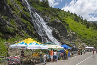 Lively atmosphere at a market stall near a large waterfall on a road, Capra Waterfall, Goat