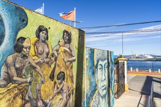 Wall of street art with images of the indigenous Yaghan people, behind a cruise ship in the