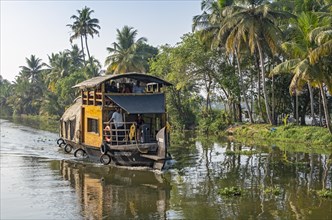 A traditional houseboat cruises along the channels near Kumarakom, offering a glimpse into the