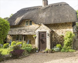Historic thatched cottage in garden at village of Sandy Lane, Wiltshire, England, UK