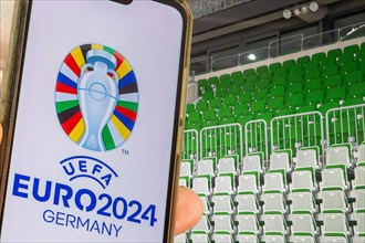 Symbolic image UEFA-EURO 2024: Smartphone with the EURO logo in front of an empty stadium
