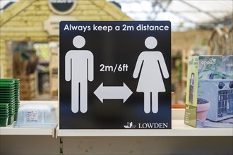 Social Distancing 2 metres apart information notice sign in Lowden garden centre shop, Wiltshire,