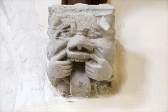 Grotesque corbel stone figure with mouth pulled open and rolling tongue, Church of Saint Nicholas,