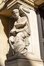 Victorian sculpture of woman reading a book outside old library building in city centre, Cardiff,