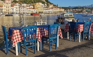 Outdoor area of a taverna with sea view, red and white tablecloths and boats, Gythio, Mani,
