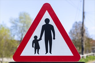 Macro close up Highway Code red triangle road sign warning of pedestrians walking, UK