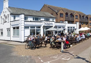People sitting in sunshine outside the Jolly Sailors pub, Pakefield, Lowestoft, Suffolk, England,