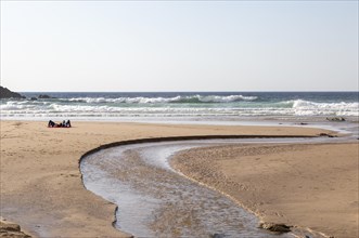 Two people lying by sea on sandy Praia Carvalhal beach, Brejao, Alentejo Littoral, Portugal,