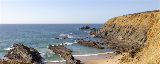 Rocky coastal landscape Praia dos Alteirinhos beach in bay with rocky headland part of Parque
