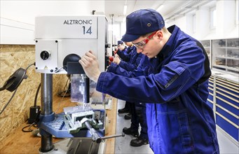A trainee mechatronics technician works with a bench drill on a workpiece in a Deutsche Bahn