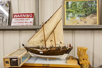 Model sailing ship and other items on display inside an auction room