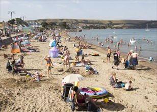 Crowded sandy beach families on summer holidays, Swanage, Dorset, England, UK