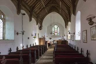 Looking east down the nave towards the altar and east window with historic wooden carved pews, fine
