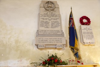 War memorial flag and poppy wreath inside the church at Tunstall, Suffolk, England, UK