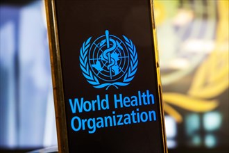 Symbolic image: Smartphone with WHO (World Health Organisation) logo against a blurred background