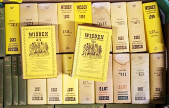 A box of Wisden Cricket almanack books on display in house clearance auction sale room, UK