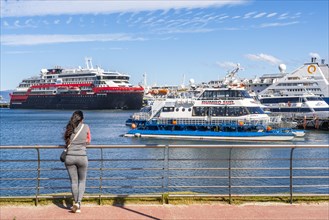 A woman watches cruise ships in the harbour on the Beagle Channel, Ushuaia, Tierra del Fuego
