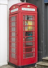 Old red telephone box used for a defibrillator, Saffron Walden, Essex, England, UK