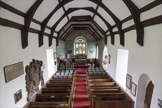 Raised angle view looking east down the nave towards the altar and east window with wooden pews,