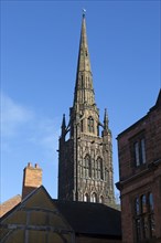 Steeple spire of old cathedral rising above historic buildings, Coventry, West Midlands, England,