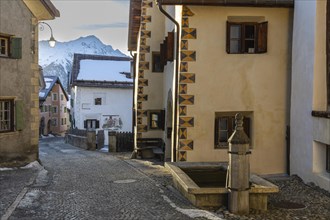 Historic houses, sgraffito, facade decorations, historic village, mountain peaks with snow, winter,