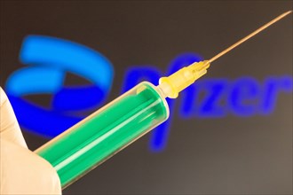 Corona vaccination/Pfizer symbol: close-up of an injection needle, with the Pfizer logo in the