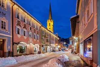 Snow-covered historic Ludwigstrasse in the Partenkirchen district with Christmas lights at dusk,