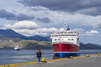 A woman watches a cruise ship named Expedition depart from the harbour of the Beagle Channel,