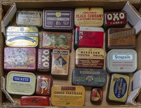 Box of old metal product tins on display at auction room