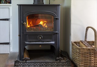Roaring flames and warm glow of home multi-fuel stove fire burning wood and coal, UK