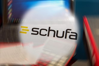 Symbolic image Schufa (information) : Schufa logo in front of a desk with tablet, calculator and