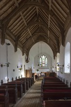 Looking east down the nave towards the altar and east window with historic wooden carved pews, fine