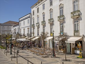 People sitting in sunshine outside street cafes in Praca da Republica, Tavira, Algarve, Portugal,